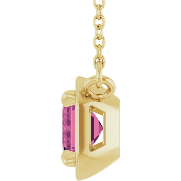 Gold pendant with a pink gemstone on a white background