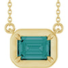Gold necklace with a green gemstone pendant on a white background