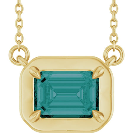 Gold necklace with a green gemstone pendant on a white background