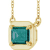 Gold necklace with a green gemstone pendant on a white background