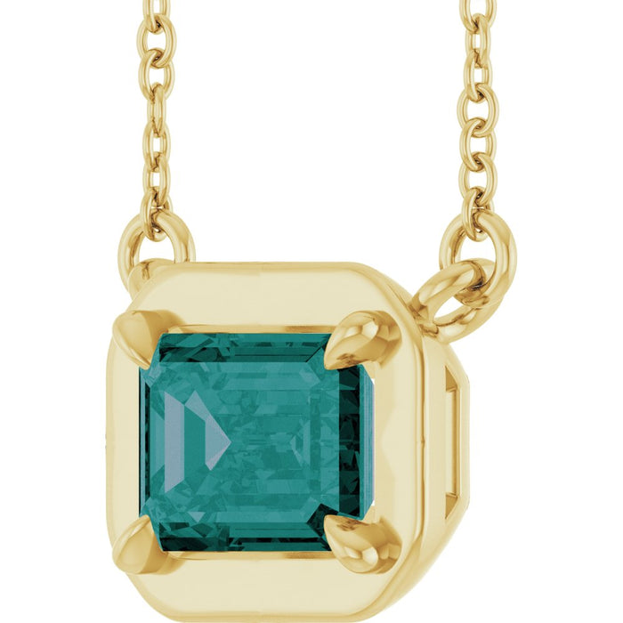Gold necklace with a green gemstone pendant on a white background