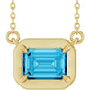 Gold necklace with a blue gemstone pendant on a white background