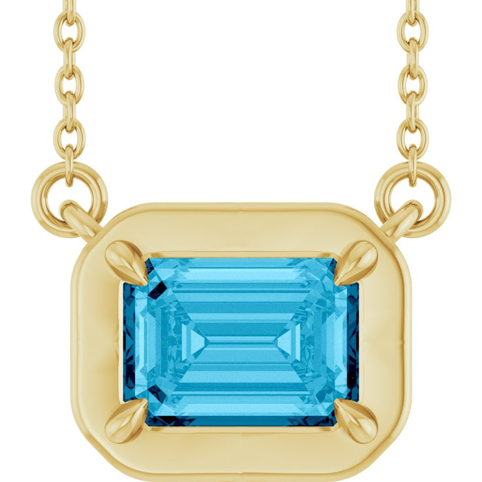 Gold necklace with a blue gemstone pendant on a white background
