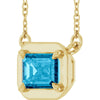 Gold necklace with a blue gemstone pendant on a white background