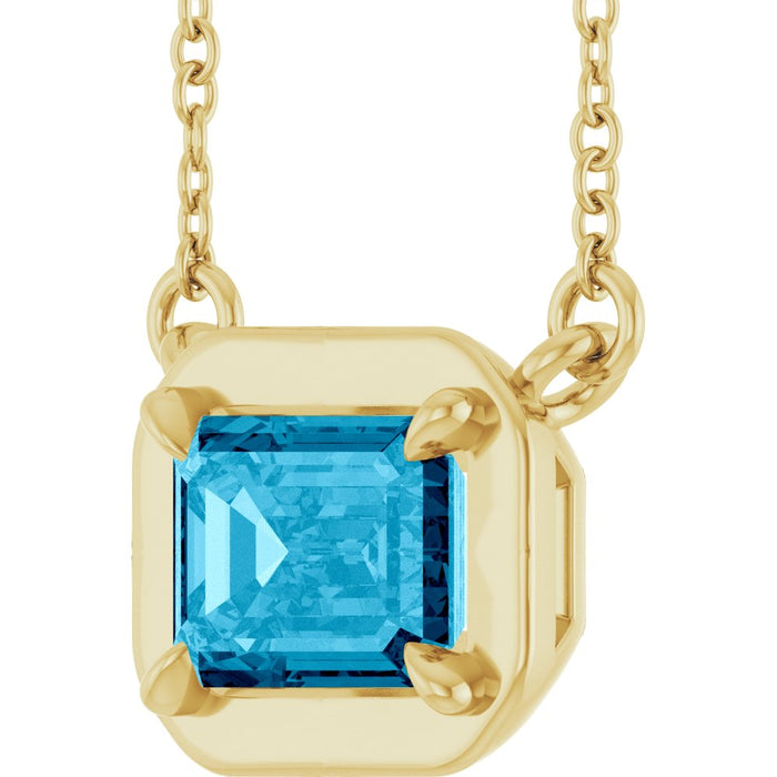 Gold necklace with a blue gemstone pendant on a white background