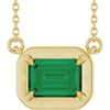 Gold necklace with a green gemstone pendant on a white background