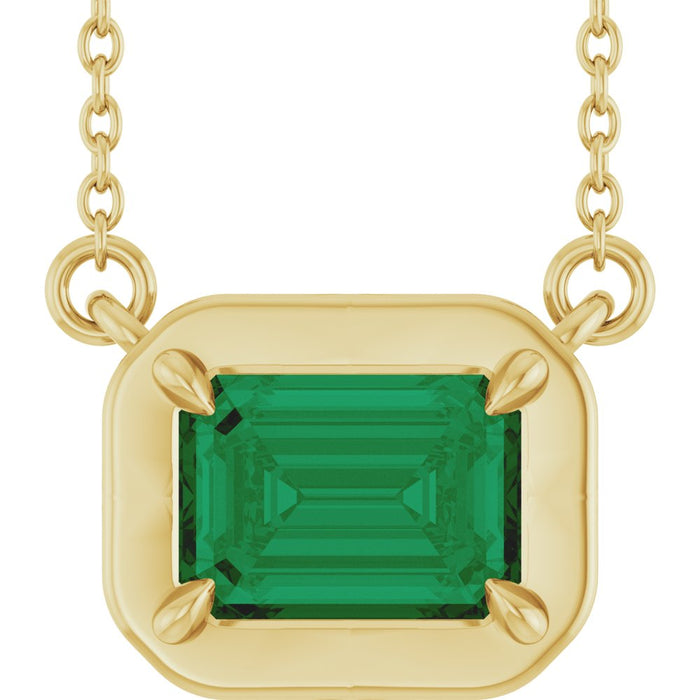Gold necklace with a green gemstone pendant on a white background
