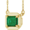 Gold necklace with a green gemstone pendant on a white background