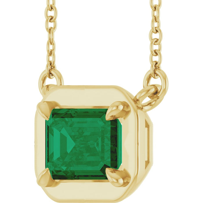 Gold necklace with a green gemstone pendant on a white background