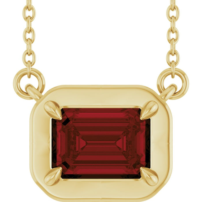 Gold necklace with a red gemstone pendant on a white background