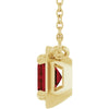 Gold pendant with a red gemstone on a white background