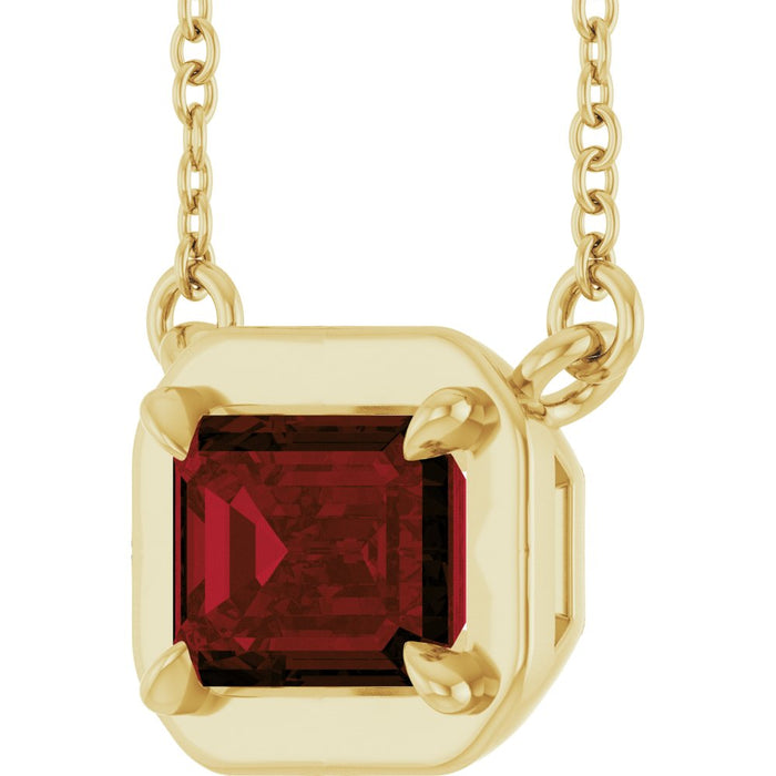 Gold necklace with a red gemstone pendant on a white background