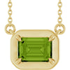Gold necklace with a green gemstone pendant on a white background