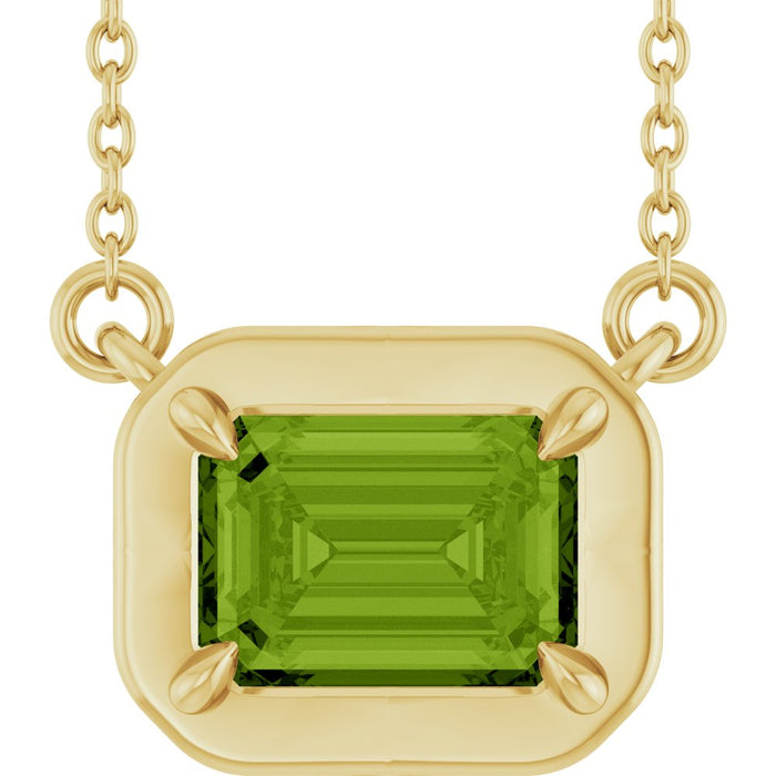 Gold necklace with a green gemstone pendant on a white background