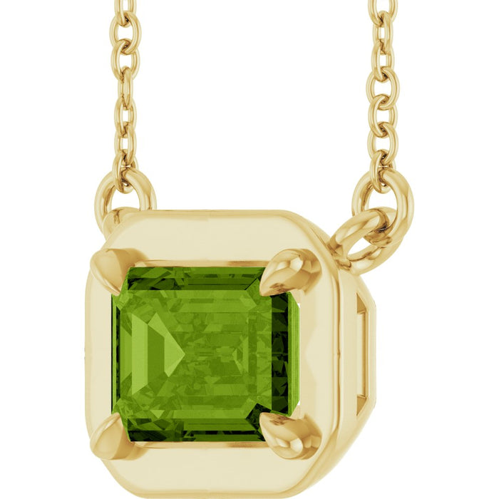 Gold necklace with a green gemstone pendant on a white background