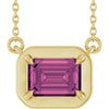 Gold necklace with a pink gemstone pendant on a white background
