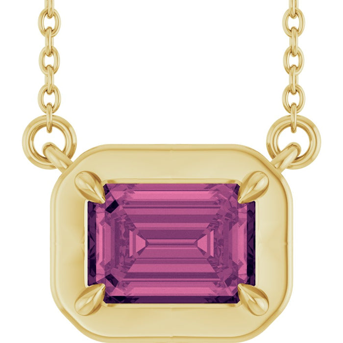 Gold necklace with a pink gemstone pendant on a white background