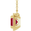 Gold pendant with a red gemstone on a white background