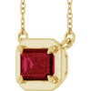 Gold necklace with a red gemstone pendant on a white background