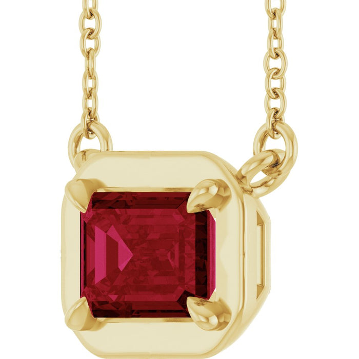 Gold necklace with a red gemstone pendant on a white background