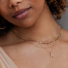 Model wearing layered solid gold and diamond necklaces. 
