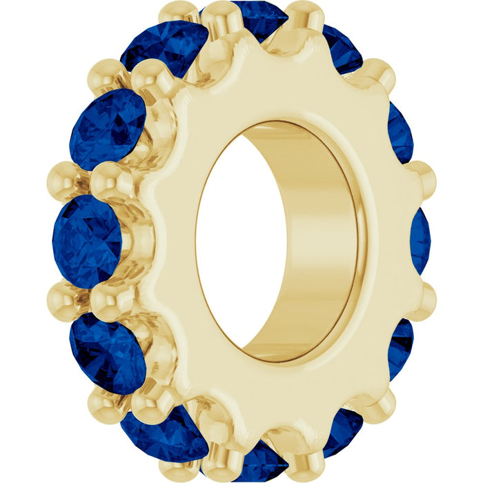 Gold charm with dark blue gemstones on a white background
