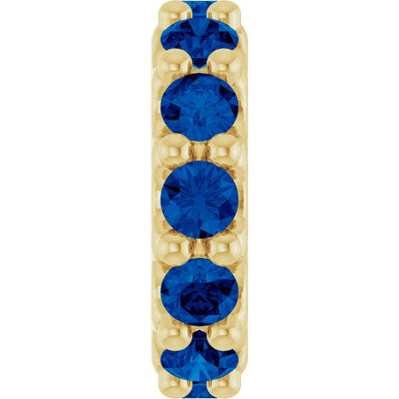 Gold charm with dark blue gemstones on a white background