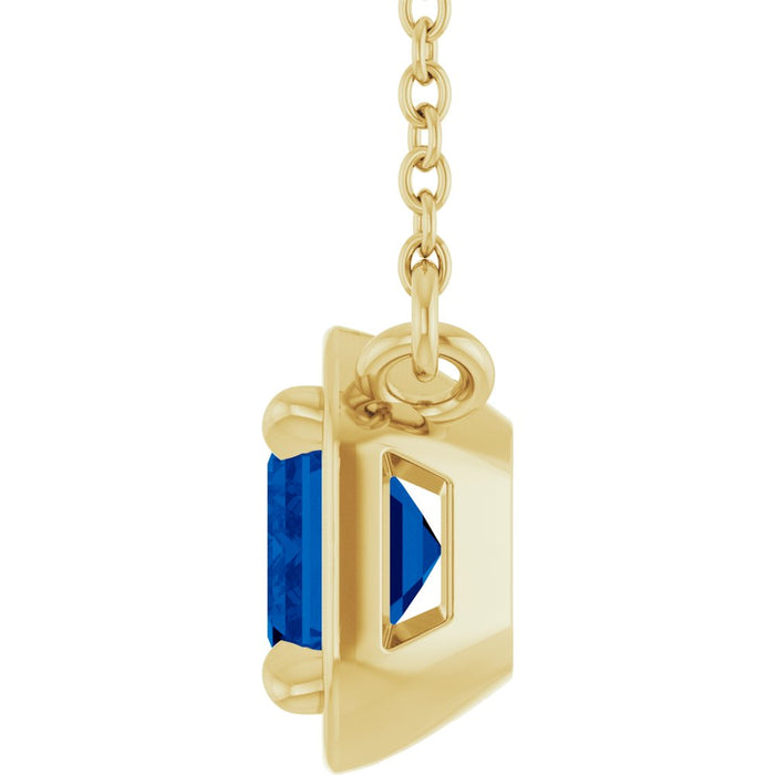Gold pendant with a blue gemstone on a white background