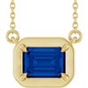 Gold necklace with a blue gemstone pendant on a white background