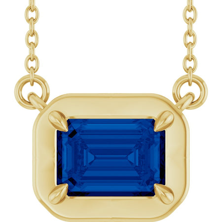 Gold necklace with a blue gemstone pendant on a white background