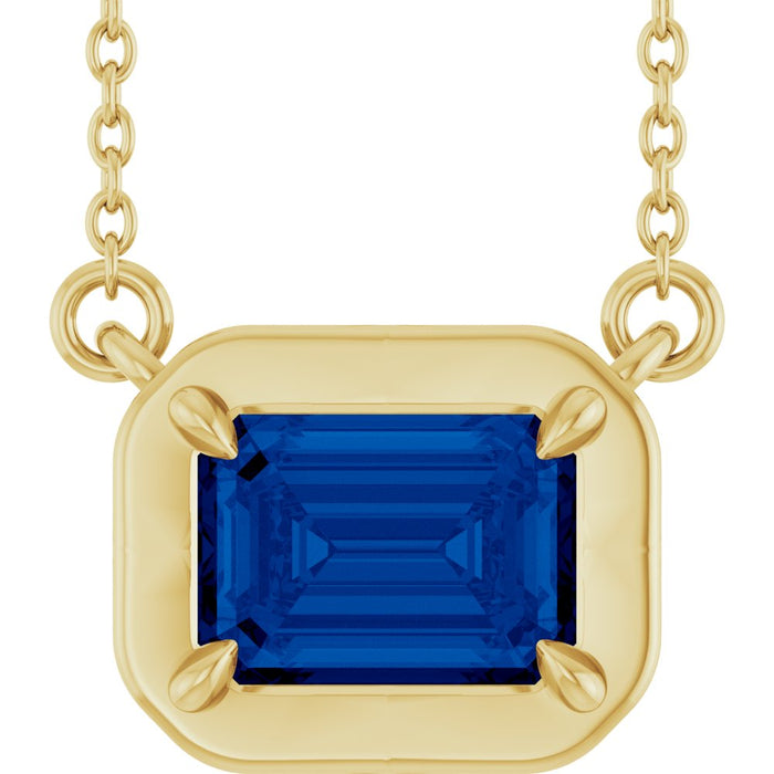 Gold necklace with a blue gemstone pendant on a white background