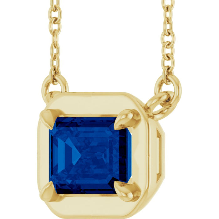 Gold necklace with a blue gemstone pendant on a white background