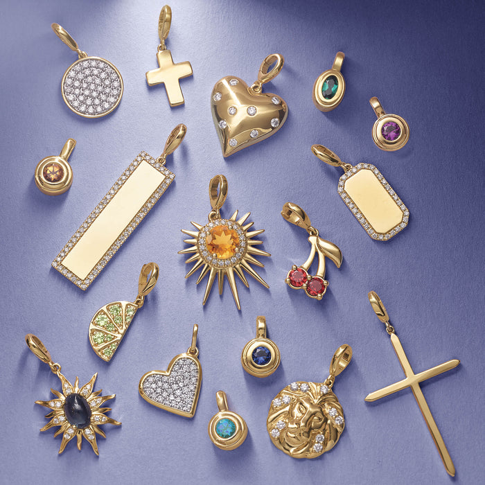 Collection of various gold pendant charms on a purple background