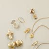 Collection of gold jewelry including rings, a necklace, and pendants on a light green background