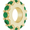 Gold charm with green gemstones on a white background