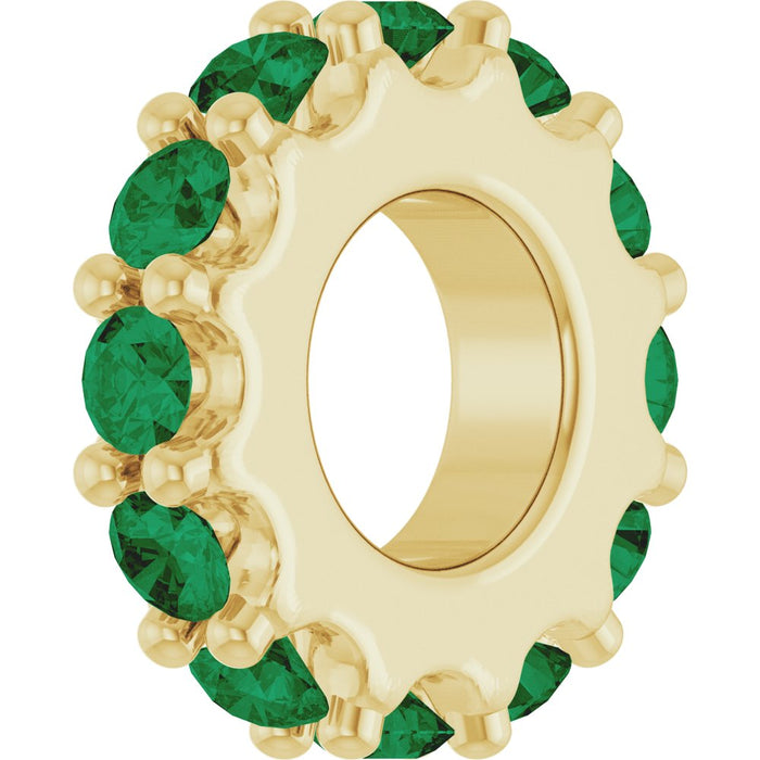 Gold charm with green gemstones on a white background