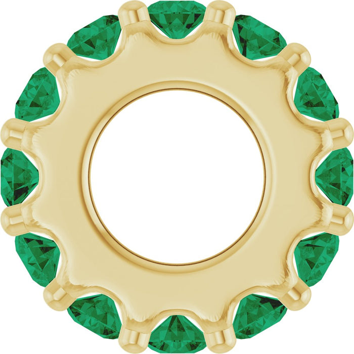 Gold charm with green gemstones on a white background