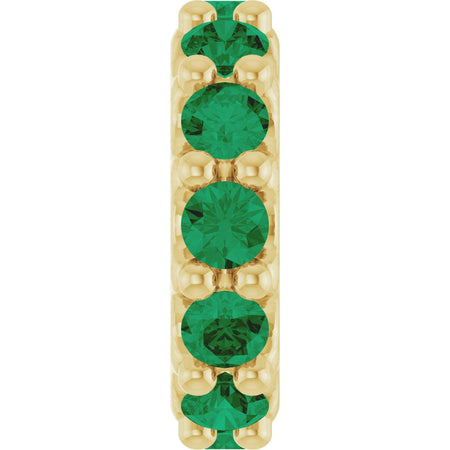 Gold charm with green gemstones on a white background