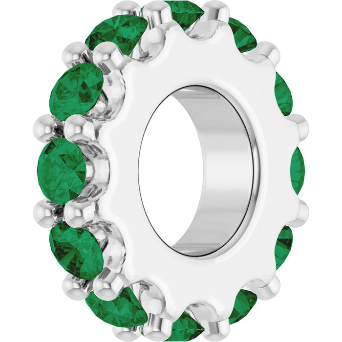 White gold charm with green gemstones on a white background