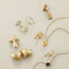 Collection of gold jewelry including rings, earrings, and necklaces on a beige background