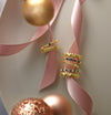 Gold rings with heart designs on a pink ribbon against a light green background