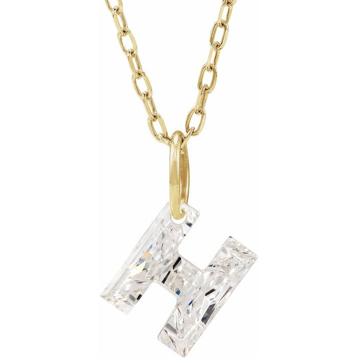 Gold necklace with a floating diamond h initial on a white background