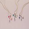 Gold necklaces with gemstone pendants on a light gray background