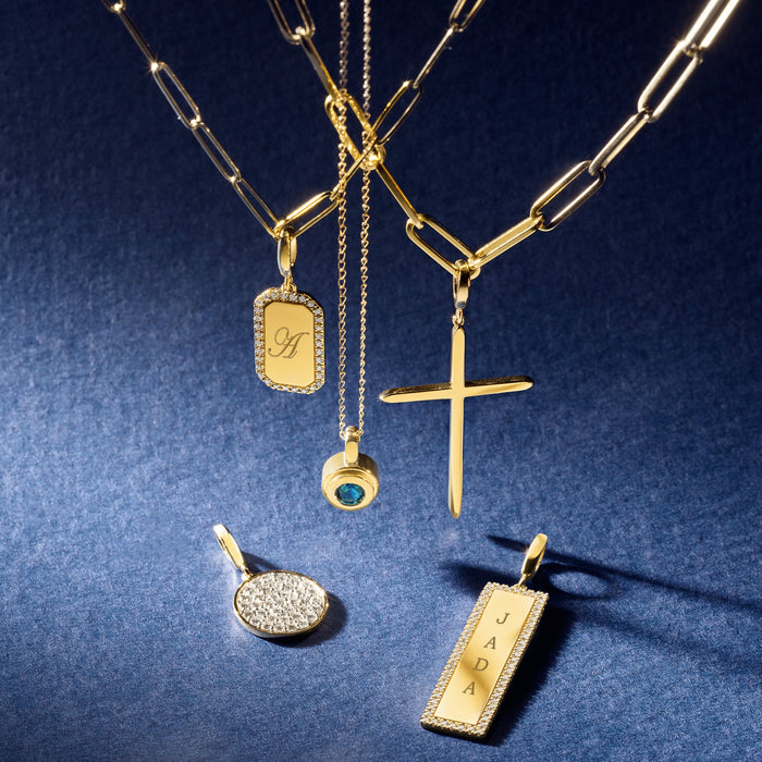 Gold necklaces with various charm pendants on a blue background