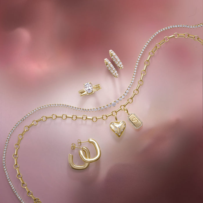Gold jewelry set including necklace, earrings, and ring on a pink floral background