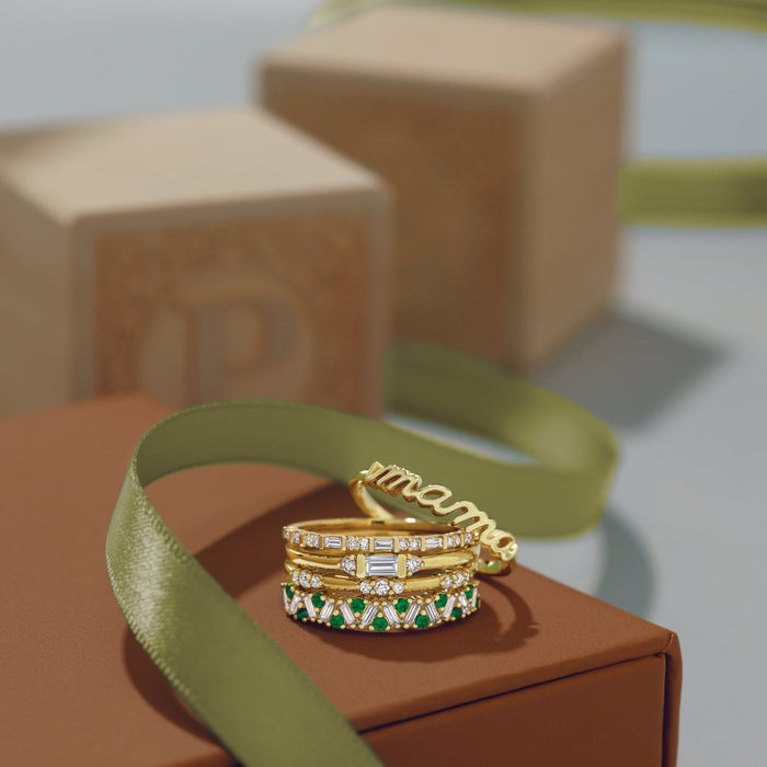 Gold and green gemstone rings on a brown box with a green ribbon