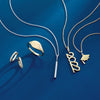 Graduation themed gold jewelry including necklaces and rings on a blue background