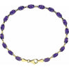 A yellow gold tennis bracelet featuring oval-cut purple amethyst gemstones, arranged in a circular shape against a solid white background.