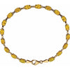 A yellow citrine gemstone tennis bracelet with oval faceted gemstones set in yellow gold, featuring a matching gold lobster clasp, shown on a plain white background.