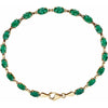 A gold-plated tennis bracelet featuring a row of oval-cut green emerald gemstones, displayed on a clean white background.